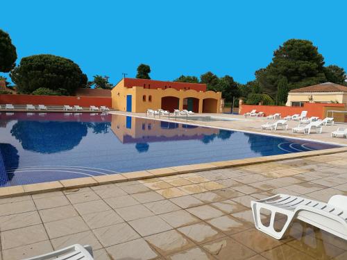 - une piscine avec des chaises longues blanches et un complexe dans l'établissement Vacargeles casa Les Mûriers et Les Chênes verts calme clim wifi animations piscine mini golf, à Argelès-sur-Mer