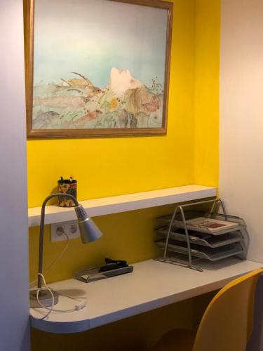 a desk with a lamp and a painting on a yellow wall at Linden-Jachthoorn in Lubbeek