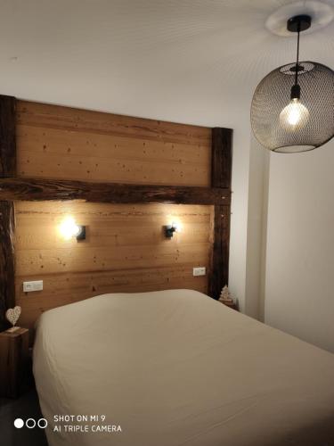 Schlafzimmer mit einem weißen Bett mit einem Kopfteil aus Holz in der Unterkunft LA BRESSE - Appartement de Charme in La Bresse