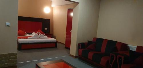 a bedroom with a bed and a couch and a chair at Meka Hotel in Dragash