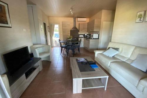 un salon avec un canapé et une table dans l'établissement Chalet 6p dans un parc résidentiel dans le Golfe de Saint Tropez (in a park in the Gulf of Saint Tropez), à Gassin