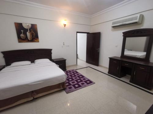 a bedroom with a bed and a dresser and a mirror at سماء البريمى للشقق الفندقية in Ţawī ‘Aqdah