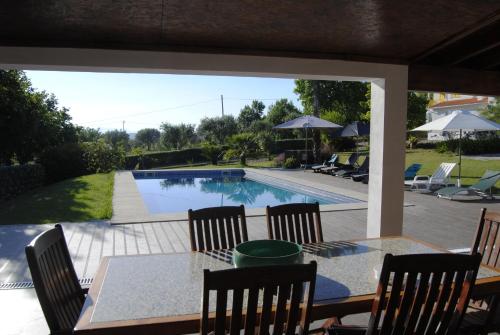 a patio with a table and chairs and a swimming pool at Quintinha Santar in Santar