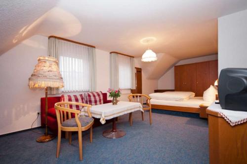 フォルバックにあるLandgasthof-Pension Ochsenのベッド、テーブル、椅子が備わるホテルルームです。