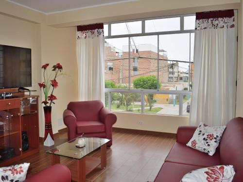 a living room with red chairs and a large window at Apartamentos Las Americas in Lima