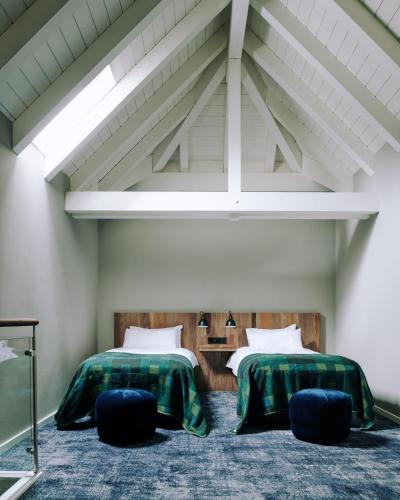 two beds in a room with two chairs at The Cambrian in Adelboden
