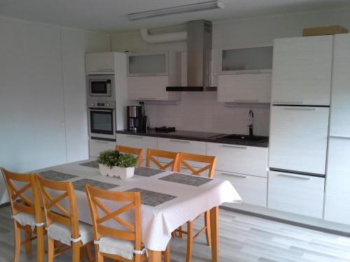 a kitchen with a table with chairs and white cabinets at Karemajat Panorama hotel in Ylitornio
