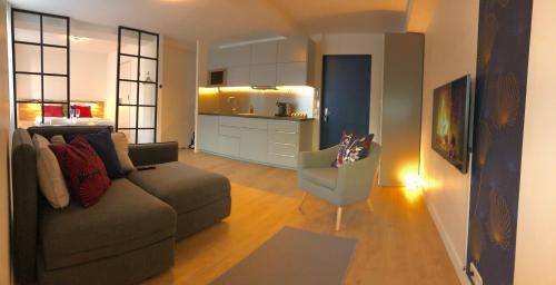 un salon avec un canapé et une cuisine dans l'établissement Appartements Les Rochelais, à La Rochelle