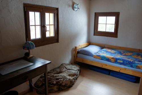 a bedroom with a bed and a desk and windows at Chalet Edelweiss in Hérémence