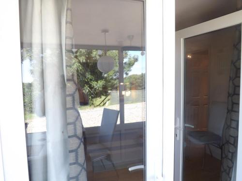 uma porta de vidro deslizante para um pátio com uma mesa e uma cadeira em The Swallows Guest House em New Quay