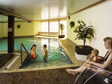 a woman with three children in a swimming pool at Hotel Central in Willingen
