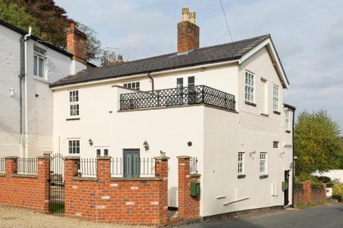 a white house with a balcony on top of it at Grundy's Lane Apartments in Malvern Wells