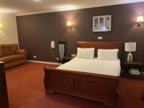 The Greyhound Hotel في لييغ: غرفة نوم بسرير واريكة وهاتف