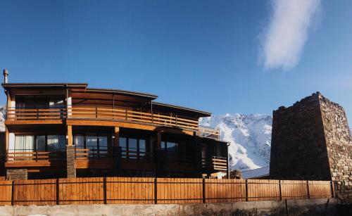 a large wooden building with mountains in the background at Capra Hotel Kazbegi in Stepantsminda