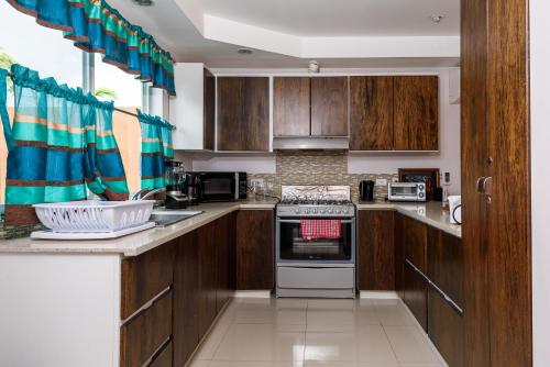 a kitchen with wooden cabinets and a stove top oven at Nzingha's Villa in Buccoo