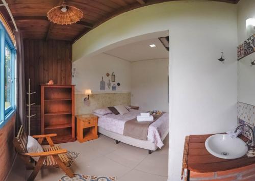 a bedroom with a bed and a sink in a room at Pousada Waikiki in Praia do Rosa