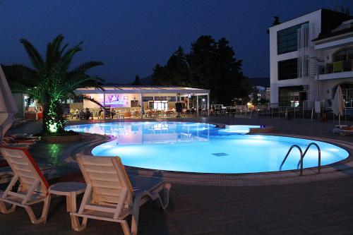 a large swimming pool with two chairs and a building at Forum Residence Hotel in Marmaris