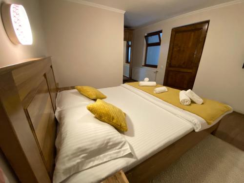 Una cama con almohadas amarillas y toallas. en Hanul Ursilor, en Chişcău