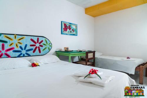 a bedroom with two beds with white sheets and a table at Pousada Cambará in Tamandaré