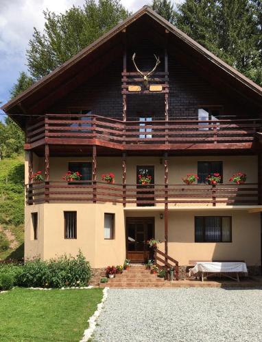a large house with a porch and a balcony at Casa Cerbu in Arieşeni