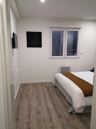 a white bedroom with a bed and a window at Les Cottages Barisiens in Bar-le-Duc