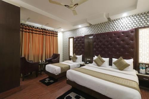a hotel room with two beds and a large headboard at Hotel Mannat international by Mannat in New Delhi