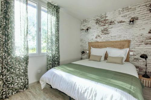 une chambre avec un grand lit et un mur de briques dans l'établissement Le Cottage Nature Syrah Clim Gaillac entre Albi-Toulouse & Les Cottages du Tarn, à Brens