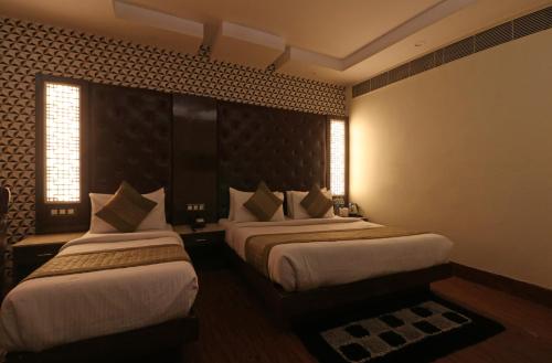 two beds in a hotel room with two windows at Hotel Mannat international by Mannat in New Delhi