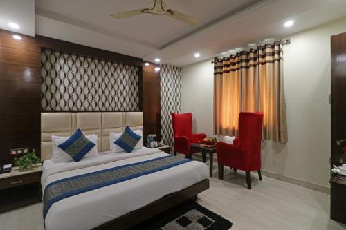 a bedroom with a bed and two red chairs at Hotel Mannat international by Mannat in New Delhi