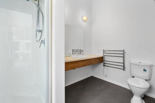 a bathroom with a toilet and a sink and a shower at Blue Gate Cottage - Waikanae Beach Holiday Home in Waikanae