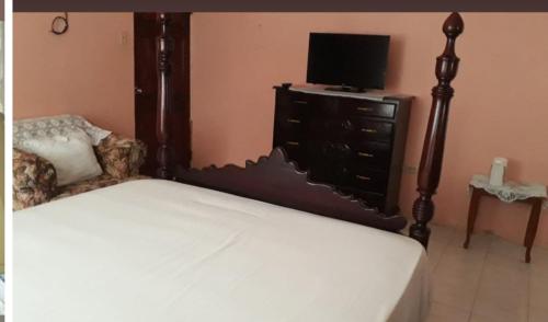 1 dormitorio con cama y vestidor con TV en Eddie's Night Rest, en Lucea