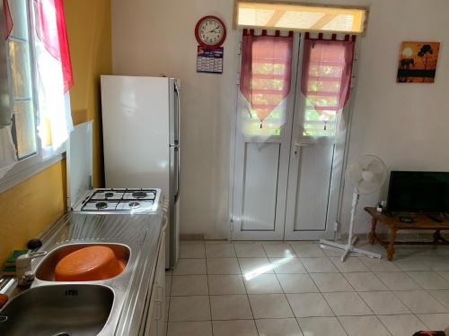 a kitchen with a stove and a sink and a refrigerator at Chez sidoine Meublé 1 chambre in Le Moule