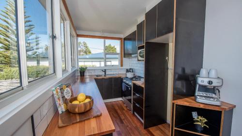 a kitchen with a table with a bowl of fruit on it at Jetty's End Bicheno in Bicheno