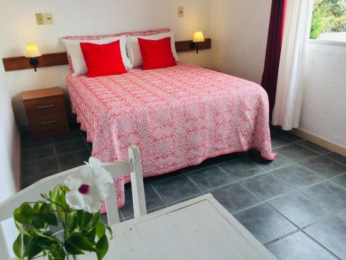 a bedroom with a bed with red pillows and a table at San Remo Terrazas Hotel in Piriápolis