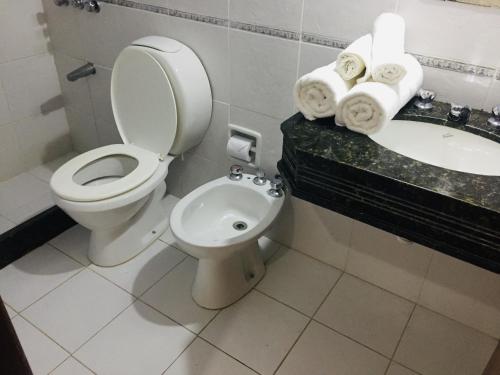 a bathroom with a toilet and a sink and towels at San Remo Terrazas Hotel in Piriápolis