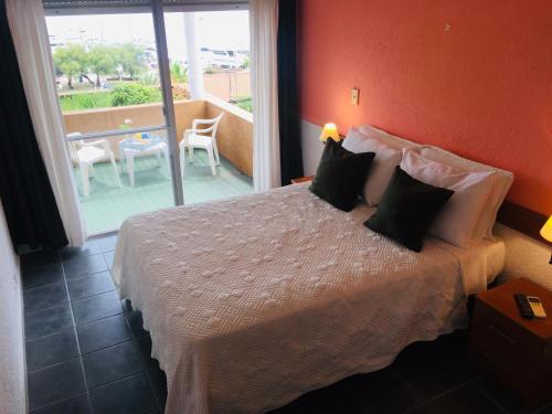 a bedroom with a bed and a balcony with a table at San Remo Terrazas Hotel in Piriápolis