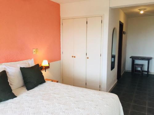 a bedroom with a white bed and an orange wall at San Remo Terrazas Hotel in Piriápolis