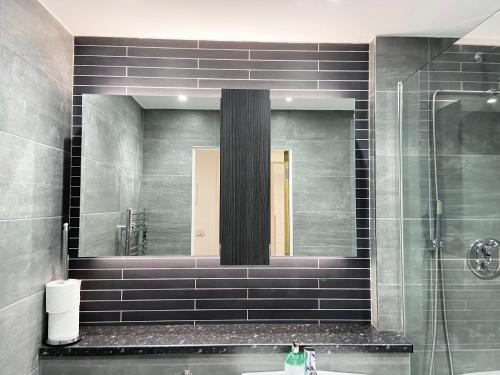 een badkamer met een spiegel en een wastafel bij The Works - Private one bedroom apartment in Manchester