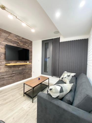 a living room with a gray couch and a table at The Works - Private one bedroom apartment in Manchester