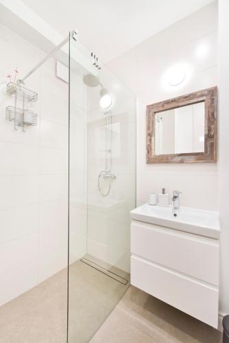 a white bathroom with a sink and a shower at Apartament Świętojańska in Gdynia