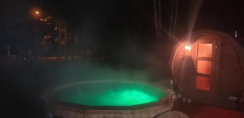 a jacuzzi tub with green water at night at Leśna Osada przy Suntago Park in Krzyżówka