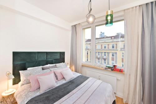 - une chambre avec un lit doté d'oreillers roses et d'une fenêtre dans l'établissement SmileApartment Świętojańska, à Gdynia