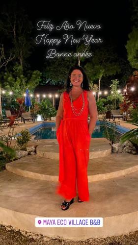 a woman in a red dress standing next to a pool at Maya Eco Village in Akumal