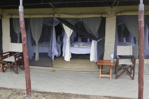 a bed in a tent with two chairs and a table at Osero Serengeti Luxury Tented Camp in Banagi