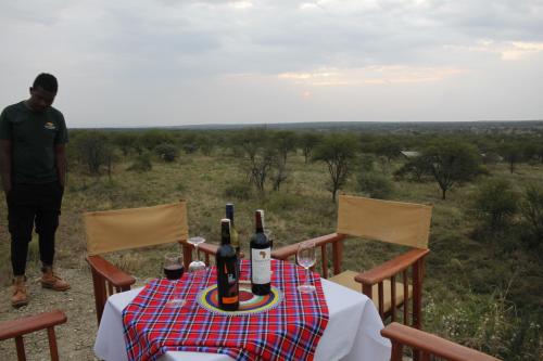 a table with bottles of wine on top of a field at Osero Serengeti Luxury Tented Camp in Banagi