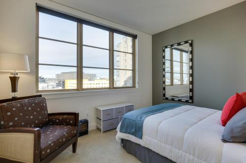 a bedroom with a bed and a chair and windows at Renu Suites at The Burlington Portland in Portland