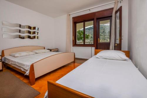 a bedroom with two beds and a window at Apartments JureG in Rogoznica