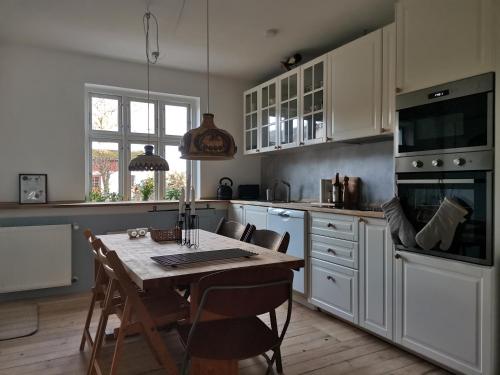 SvebølleMikrogaarden shared kitchen&bathroom的一间带木桌的厨房和一间带白色橱柜的厨房