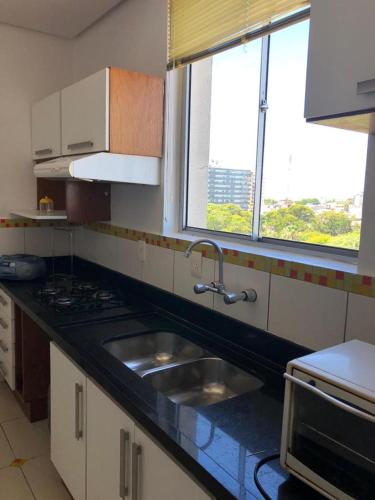 a kitchen with a sink and two windows at Apartamento Bela Vista in Uruguaiana