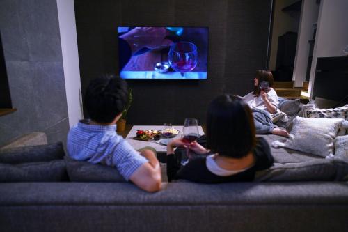 a group of people sitting in a living room watching tv at 20 PIECES in Kyoto